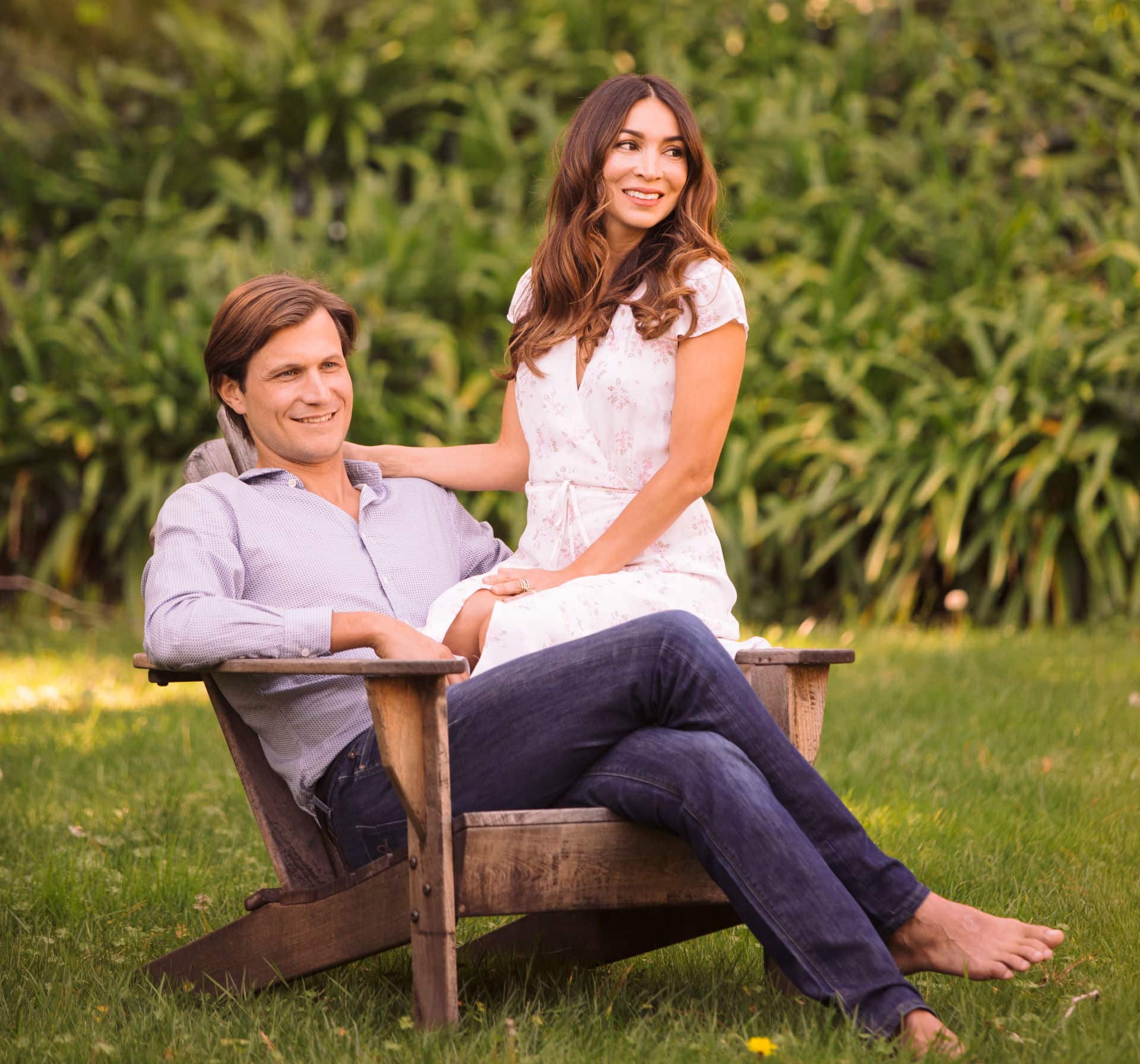 A man and woman sitting on top of a wooden bench.
