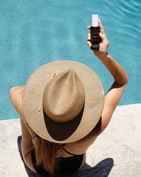 A woman in a hat is holding up her phone