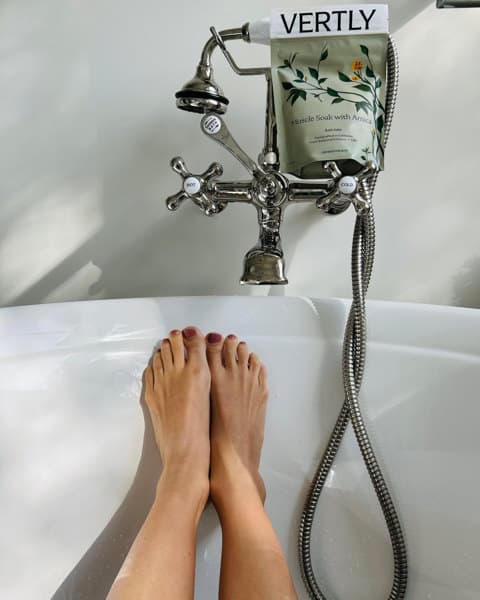 A person 's feet in the tub with their legs crossed.